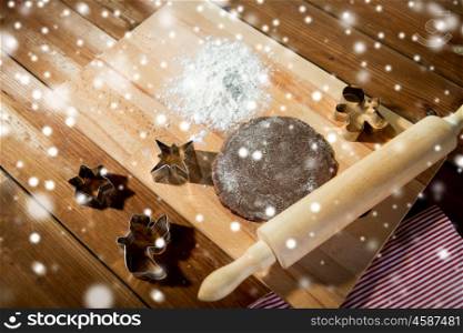 baking, cooking, christmas and food concept - close up of gingerbread dough, metal molds and rolling pin with flower on wooden cutting board at home kitchen from top