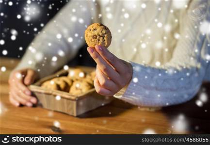 baking, cooking, people and food concept - close up of woman with oat cookies sitting at wooden table at home