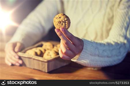 baking, cooking, people and food concept - close up of woman with oat cookies sitting at wooden table at home. close up of woman with oat cookies at home