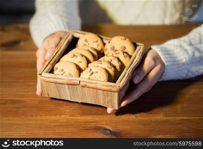 baking, cooking, people and food concept - close up of woman with oat cookies sitting at wooden table at home