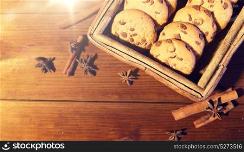 baking, culinary, holidays and food concept - close up of oat cookies in wooden box, and cinnamon on table. close up of oat cookies on wooden table