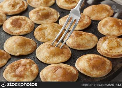 Baking Dutch mini pancakes called poffertjes in a special skillet pan