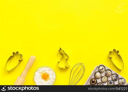 Baking Easter composition. Rolling pin, whisk for whipping, cookie cutters, quail eggs flour on yellow paper background. Top view Copy space Creative happy easter concept Template for text or your design. Baking Easter composition. Rolling pin, whisk for whipping, cookie cutters, quail eggs flour on yellow background. Top view Copy space Creative happy easter concept Template for text or your design