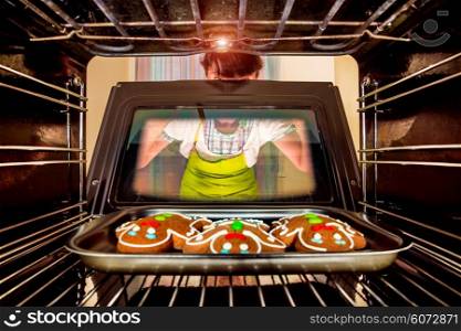 Baking Gingerbread man in the oven, view from the inside of the oven. Cooking in the oven. Focus not on cookies focus on woman