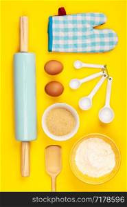 Baking or cooking ingredients on yellow background, flat lay. Ingredients, kitchen items for baking. Kitchen utensils, flour, eggs, sugar. Text space, top view.. Baking or cooking ingredients on yellow background, flat lay