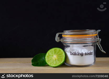 Baking soda with lemon on wooden on black background