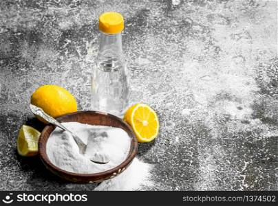 Baking soda with vinegar and lemon. On rustic background.. Baking soda with vinegar and lemon.