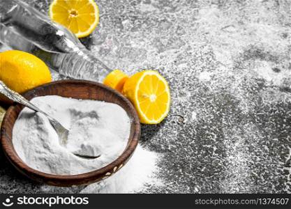 Baking soda with vinegar and lemon. On rustic background.. Baking soda with vinegar and lemon.