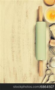 Baking tools and ingredients - flour, rolling pin, eggs, measuring spoons on vintage wood table. Top view. Rustic background with free text space