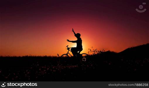 Balance, Enjoying Life and Harmony Concept. Silhouette of Happiness Person on Bicycle with raised arms to Balancing Body during Sunrise or Sunset in Nature Public Park