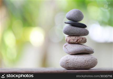 Balance Stones stacked to pyramid in the soft green background.. Balance Stones stacked to pyramid in the soft green background to Spa ideas design or freedom and stability concept on rocks.