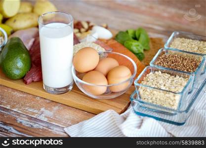 balanced diet, cooking, culinary and food concept - close up of eggs, cereals and milk glass on wooden table