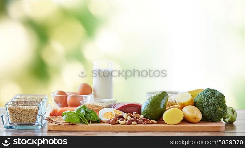 balanced diet, cooking, culinary and food concept - close up of vegetables, fruits and meat on wooden table over green natural background