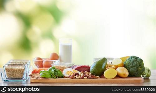 balanced diet, cooking, culinary and food concept - close up of vegetables, fruits and meat on wooden table over green natural background