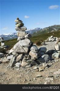 balanced stack of stones at Eidfjorden, Norway with snow and mountains as background