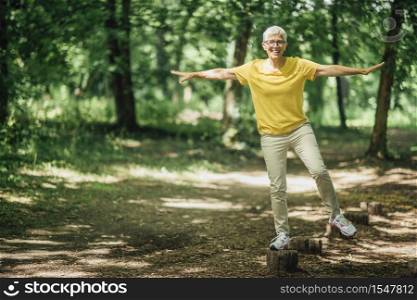 Balancing exercise outdoors. Mature woman standing on one leg, exercising balance . Balancing Exercise Outdoors