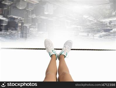 Balancing on rope. Top view of person standing on rope above city