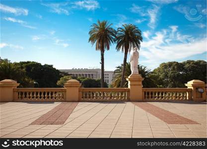 balcony with a statue on a background of palm trees and blue sky