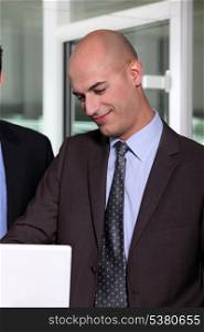 Bald businessman showing funny e-mail to colleague