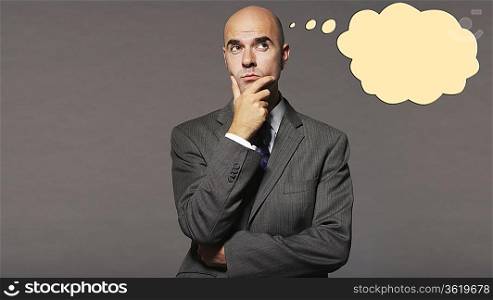 Bald businessman thinking with speech bubble over gray background