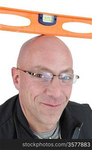 Bald man balancing spirit-level on his head