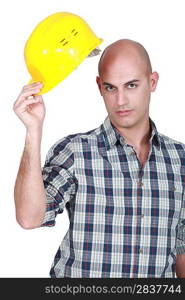 Bald young builder lifting hat
