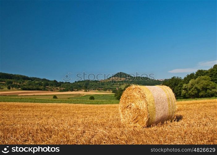 bale of straw with a panoramic view to a hill. grain harvest