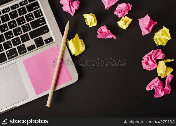 ball crumpled papers with adhesive note pencil laptop against black background