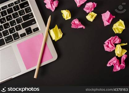 ball crumpled papers with adhesive note pencil laptop against black background