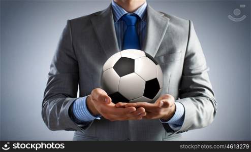 Ball in hands. Close up of businessman holding soccer ball in hand