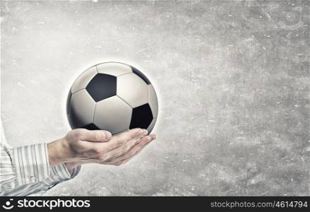 Ball in hands. Close up of businessman holding soccer ball in hand