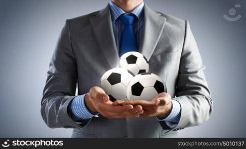 Ball in hands. Close up of businessman holding soccer ball in hand