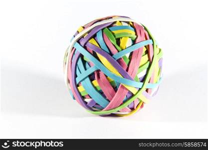 Ball of brightly coloured rubber bands, white background, slight shadow