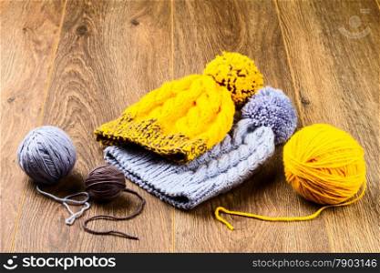 ball of threads and knitting caps on wooden background