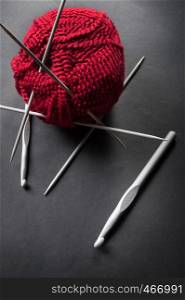 ball of wool and knitting needles on dark background