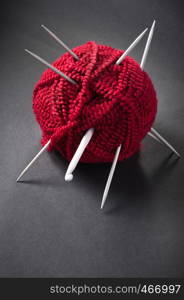 ball of wool and knitting needles on dark background