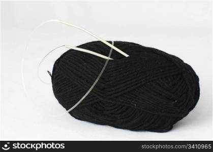 Ball of yarn and knitting skewers. Black yarn on white background
