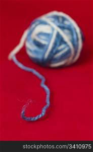 Ball of yarn and knitting skewers. Blue and white color balls on red background