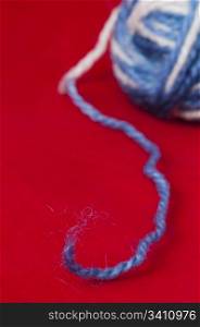 Ball of yarn and knitting skewers. Blue and white color balls on red background