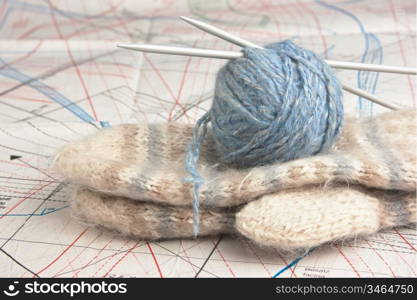 ball of yarn and mittens on a background pattern