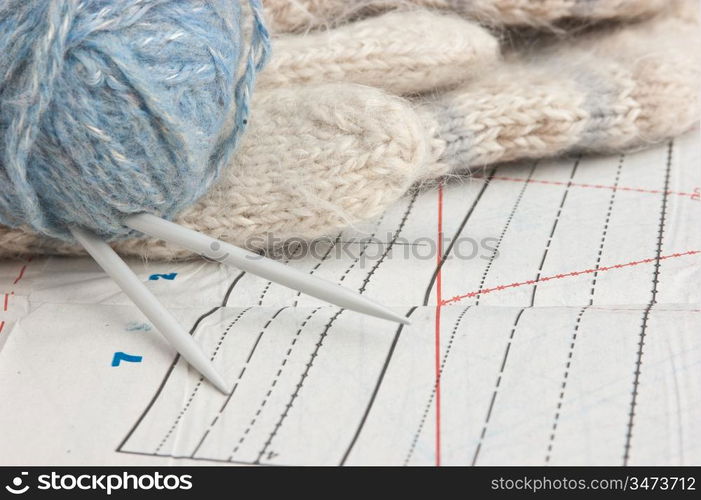 ball of yarn and mittens on a background pattern