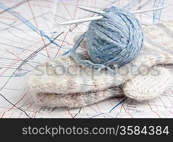 ball of yarn and mittens on a background pattern