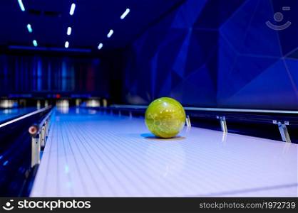 Ball on lane, bowling game concept, nobody. Pins on blur background, alley or entertainment center interior, selective focus on bowl. Ball on lane, bowling game concept, nobody