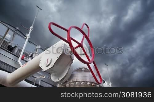 ball valve on cooling installations at gas compressor station against background of thunderstorm sky, timelapse, closeup