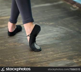 Ballerinas legs in black pointes on wooden floor in point position