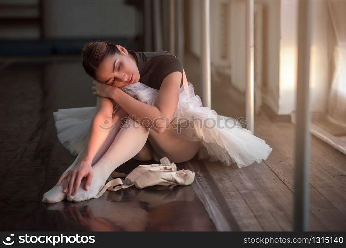 Ballet dancer sitting on the floor in dark class after rehearsal.