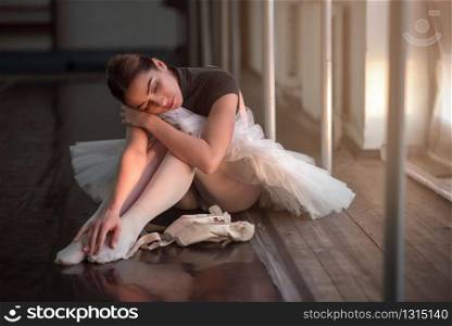 Ballet dancer sitting on the floor in dark class after rehearsal.
