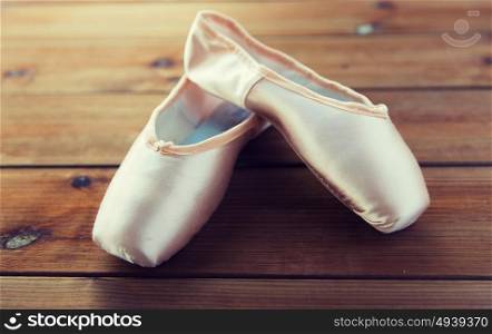 ballet, footwear and objects concept - close up of pointe shoes on wooden floor. close up of pointe shoes on wooden floor