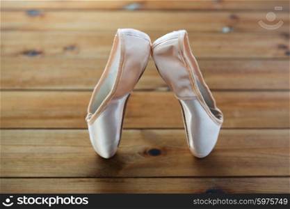 ballet, footwear and objects concept - close up of pointe shoes on wooden floor