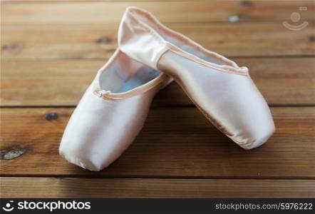 ballet, footwear and objects concept - close up of pointe shoes on wooden floor